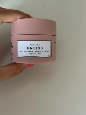 Maria Nila Gneiss Moulding Paste 100 ml - Säljer en rosa burk Maria Nila Gneiss Moulding Paste, 100 ml. Vegansk och djurvänlig stylingpasta med växtbaserade proteiner, tillverkad i Sverige. Perfekt för att forma och styla håret med naturlig känsla.
