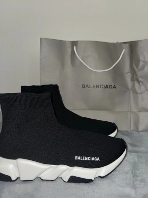  Speed Trainer svarta vita sneakers - Svart vita Speed Trainer sneakers med vit chunky sula och stickad ovandel i textil. Strumpliknande passform och B-logga på sidan. Perfekta för dig som gillar en modern och clean stil.