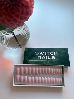 Ljusrosa press-on naglar Switch Nails - Säljer ett set med ljusrosa press-on naglar från Switch Nails. Naglarna har en mjukt oval form och en glansig finish. Tillverkade av återvunnet material och kommer i en snygg grön förpackning. Perfekt för dig som vill fixa naglarna snabbt och enkelt.