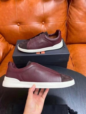 Slip-on sneakers i vinrött och brunt - Snygga slip-on sneakers i vinrött och mörkbrunt läder med matchande mockadetaljer på tån. Skorna har en stilren design utan synliga snören och en vit, chunky sula som ger en modern look. Perfekta för dig som gillar minimalistisk stil och vill ha något unikt till din outfit. Dm mig för mer info