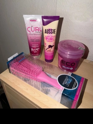 Kit för lockigt hår med borste - Säljer ett kit för lockigt hår som innehåller en rosa detangling-borste i plast, curl cream från The Curl Company och Aussie samt en burk Eco Curl & Wave gel. Alla produkter är oöppnade. Köpta för ca en månad sen.