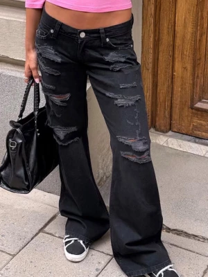 Svarta utsvängda ripped jeans - Säljer ett par svarta jeans med utsvängda ben och flera stora slitningar framtill. Storlek xs från Gina🩷