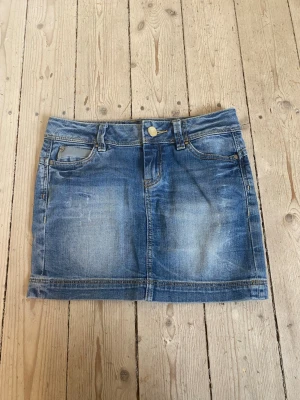Lågmidjad blå jeanskjol - Snygg lågmidjad blå jeanskjol i kort modell. 