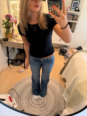 Blå bootcut jeans med låg midja - Säljer ett par klassiska blå bootcut jeans med låg midja och raka ben. Jeansen har fem fickor och bälteshällor, perfekta för en avslappnad och trendig look. Materialet är mjukt denim i bomull. Passar dig som gillar 00-talsstil!