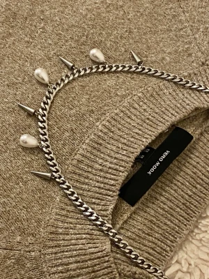 Kedjehalsband med pärlor och spikes - Säljer ett chunky silverfärgat kedjehalsband med droppformade vita pärlor och metallspikar som hängande detaljer. Halsbandet har en edgy och modern look, perfekt för dig som vill sticka ut. Materialet är rostfritt och pärlor i en cool mix.