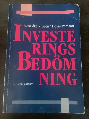 Investeringsbedömning Liber Ekonomi - Kursbok i investering och ekonomi, skriven av Sven-Åke Nilsson och Ingvar Persson. Omslaget är blått med stora rosa bokstäver och vita detaljer. Perfekt för dig som pluggar ekonomi eller behöver fördjupa dig i investeringsbedömning.