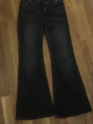 Svarta utsvängda jeans - Snygga svarta jeans med utsvängda ben och klassisk femficksmodell. Jeansen har en mörk tvätt och markerade sömmar. Perfekta för dig som gillar retrostil och vill ha ett par bekväma och trendiga byxor.