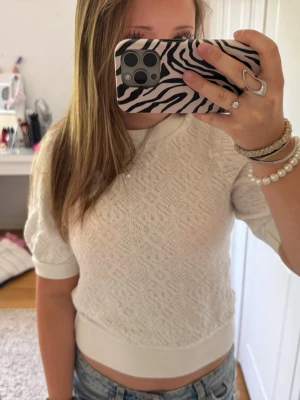 Vit kortärmad tröja Holly & Whyte - Säljer en vit kortärmad tröja från Holly & Whyte by Lindex. Tröjan har ett diskret mönster i tyget, ribbade muddar vid ärmslut och nederkant samt rund halsringning. Perfekt till jeans eller kjol för en fräsch look.