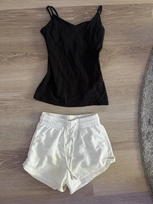 Vita shorts med snörning från H&M & lager 157 t-shirt - Säljer ett par vita shorts från H&M i mjuk bomullsmix. De har elastisk midja med snörning och avslappnad passform och ett svart linne I storlek M, men passar som en lite lite lös S. Shortsen rätt storlek xs, inga hål eller fläckar.