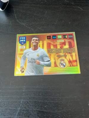 FIFA 365 Cristiano Ronaldo samlarkort - Säljer ett FIFA 365 Limited Edition samlarkort med Cristiano Ronaldo från Real Madrid. Kortet har en glansig yta med färgstark design och visar statistik som 81, 104 och 110. Perfekt för dig som gillar fotboll och samlar på Panini-kort.