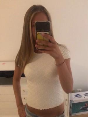 Vit croppad topp med struktur - Säljer en creamy vit croppad topp med korta ärmar och snygg struktur i tyget. Toppen har en tight passform och vågig kant nertill. Aldrig använd! I storlek 158/162 men är som xs!💕