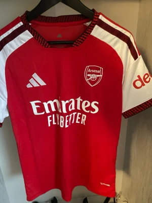 Arsenal hemma fotbollströja 26/27 - Helt ny och trendig Arsenal 2026 / 2027 säsongs Hemma version fotbollströja. Nypris runt 1099kr. Passformen på tröjan är som en oversized t-shirt i storlek S. Tröjan kommer med original förpackning och skickas i förstärkt påse för att hindra skador eller slit under frakt. Kontakta vid funderingar, och kolla min profil om du vill se andra tröjor.