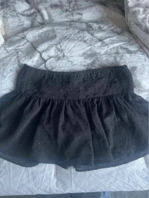 🖤 Gina Tricot svart lågmidjad glitterkjol | 146/152 (passar XXS/XS) - Säljer en supersnygg svart lågmidjad kjol från Gina Tricot med fint glitter i tyget som glittrar snyggt i ljuset. Märkt 146/152, men passar även XXS/XS beroende på hur du vill att den ska sitta.Perfekt till fest, nyår, middag eller när du vill piffa upp en outfit. Superfin att matcha med ett vitt linne, en söt topp eller en stickad tröja.