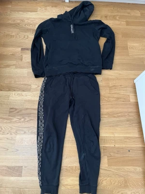 hugo tracksuit i svart o vit text  - svart hugo travsksuot tröja. är storlek S och byxan xs skulle säga att hela travksuiten sitter som s den har inga skador lite tecken på användning men inget värsta elller farligt har byten beror på vad och pris kan alltid diskuteras 