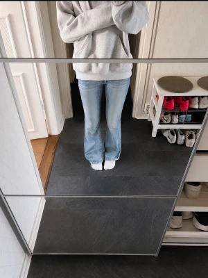 Ljusblå bootcut jeans med nitar - Säljer ett par ljusblå bootcut jeans med snygga detaljer på bakfickan, inklusive dekorativa nitar. Jeansen har klassisk femficksdesign och är tillverkade i denim med lätt tvättad look. Perfekta för en avslappnad och trendig stil.