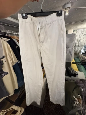 Vita chinos från Dickies - Säljer ett par klassiska vita chinos från Dickies med raka ben och diskreta bakfickor. Byxorna har hällor för bälte och stängs med dragkedja och knapp. Perfekta för dig som gillar en clean och enkel stil. Finns att hämta i Gröndal. Passar till nån som är 170-180 cm lång 