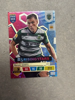 FIFA 365 Panini fotbollskort Ugarte - Säljer ett FIFA 365 Panini fotbollskort med Manuel Ugarte från Sporting CP. Kortet har färgstark design med texten 'Rising Stars' och spelarens statistik. Perfekt för samlare av fotbollskort eller Panini-serien.