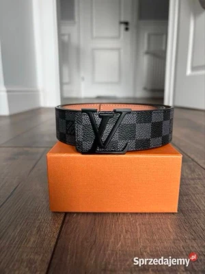 Svart rutigt IV bälte - Snyggt svart bälte från Iv med klassiskt rutigt mönster och stor IV-logga i metall framtill. Bältet har en stilren design och är gjort i skinn med detaljer i svart. Perfekt accessoar för att lyfta din outfit.