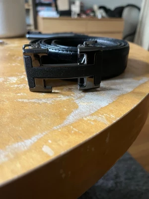 Snyggt svart skärp med H logga på.  - Ett snyggt och lyxigt skärp. Med ett H i metal på. Ger en lyxig känsla och look. Knappt använt. 110cm! 