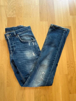 Dondup jeans - Snygga blå skinny jeans med slitningar och tvättade detaljer från dondup. Jeansen har fem fickor, normal midja och smal passform. Tillverkade i denim med stretch för extra komfort. Perfekta för en avslappnad och trendig look. Modellen är Ritchie och är storlek 29