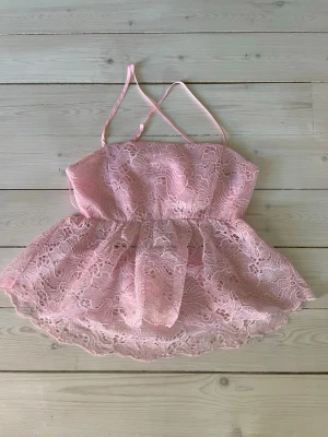 Rosa spetslinnetopp från BikBok - Supersöt rosa linnetopp från BikBok med tunna axelband och volangig spets över hela toppen. Insidan är fodrad med mjukt satinliknande tyg och ryggen har smock för extra komfort. Perfekt för dig som vill ha en romantisk och feminin look.
