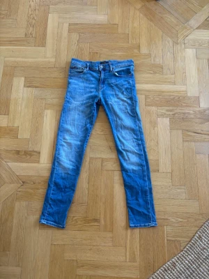 Blå jeans från Polo Ralph Lauren - Säljer ett par blå jeans från Polo Ralph Lauren med klassisk femficksmodell och dragkedjegylf. Jeansen har snygga slitningar och tvättade detaljer för en avslappnad look. Perfekta till sneakers eller boots. bakfickorna  på jeansen finns de små hål, finns bild på hålen. Storlek på jeansen är 16 år och dem är i fint skick.