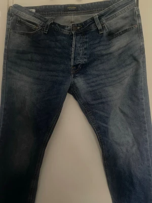 Blå jeans från Jack & Jones - Snygga jeans från Jack & Jones med klassisk femficksdesign och subtila slitningar. Jeansen har raka ben och är tillverkade i ett mjukt denimtyg som ger en bekväm passform. Perfekta för en avslappnad och trendig look.