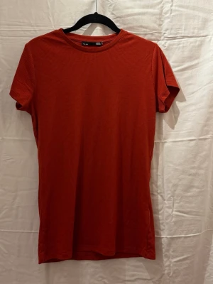 Röd ribbad t-shirt - En enkel och stilren t-shirt med ribbad struktur. T-shirten har korta ärmar och rund halsringning. Perfekt basplagg till garderoben och lätt att matcha med olika stilar. Väldigt stretchig. Lappen är borta men skulle säga det passar s/m då