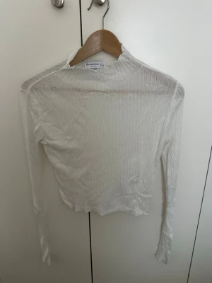 Vit ribbad långärmad topp Stradivarius - Säljer en tunn, vit långärmad topp från Stradivarius. Toppen är ribbad med hög hals och har en lätt transparent look. Perfekt att styla lager på lager eller bära som den är för en clean vibe.
