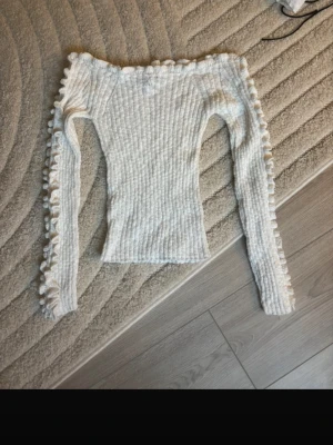 Vit stickad tröja från Lindex - Supersöt vit stickad tröja från Lindex i storlek XS. Tröjan har långa ärmar och volanger längs ärmarna och halsringningen. Smal passform och ribbad struktur.
