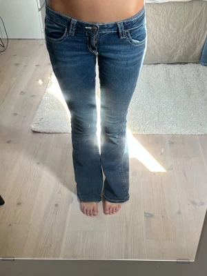 Blå bootcut jeans med kontrastsömmar - Snygga blå bootcut jeans med låg midja och vita kontrastsömmar. Jeansen är från Gina tricot och är väldigt trendiga, de har markerade bakfickor med dekorativa sömmar. Perfekta för en avslappnad och trendig look.