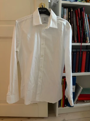 Vit klassisk skjorta från Bläck - Säljer en stilren vit skjorta från Bläck. Skjortan har lång ärm, klassisk krage och knappar framtill. Perfekt till både jeans och kostymbyxor. Tillverkad i bomull för en skön känsla och snygg passform.