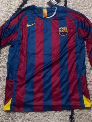 Nike Barcelona 2005/06 Total 90 Ronaldinho #10 – Limited Edition | Size XXL - Own a piece of football history with the iconic Nike FC Barcelona 2005/06 “Total 90” Ronaldinho Reissue Jersey. Inspired by one of the most legendary eras of Barcelona football, this limited edition shirt celebrates the magic of Ronaldinho 🇧🇷 and the unforgettable 2005/06 season. 🔵🔴 FC Barcelona 2005/06 Total 90 Reissue * ⭐ Ronaldinho inspired design 🇧🇷 * 🏆 Limited Edition release * 👕 Iconic retro Nike style * 💨 Comfortable & lightweight material * ⚽ Perfect for collectors, fans, and casual wear