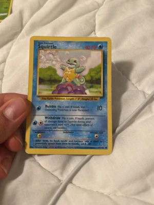 Squirtle Pokémonkort Base Set - Säljer ett klassiskt Squirtle Pokémonkort från Base Set. Kortet har blå ram och motiv av Squirtle som blåser bubblor. Text och effekter på engelska. Perfekt för samlare eller dig som gillar Pokémon!