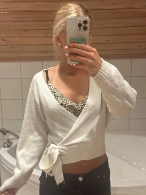 Vit stickad omlottkofta med knytband - Snygg vit omlottkofta med knytband i midjan och långa ärmar. Tröjan är från even and odd och är i storlek xs. Superskönt material och i fint skick. Skriv för fler bilder.💕