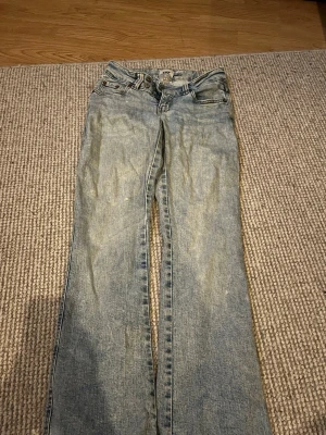 Ljusblå bootcut jeans med brodyr - Säljer ett par ljusblå bootcut jeans med snygg brodyr på bakfickorna. Jeansen har klassisk femficksmodell och är tillverkade i denim. Perfekta för dig som gillar en avslappnad men ändå trendig look. Pris diskuteras 