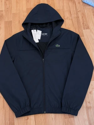 Lacoste Jacka - Tjena, jag säljer en riktigt snygg och populär Lacoste jacka😁 Dragkedjan är lite sönder men den är i mycket bra skick och är helt ny med prislapparna kvar!☺️ Den är självklart äkta✅ Skicka om du har några frågor😄