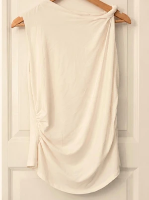 Beige/vit oneshoulder topp - Trendig beige oneshoulder topp med draperad effekt och knutdetalj på axeln. Tunn och mjuk, perfekt för en stilren look. Toppen är ärmlös på ena sidan och har en asymmetrisk siluett som ger en modern känsla💕DM FÖR FLER BILDER 💕