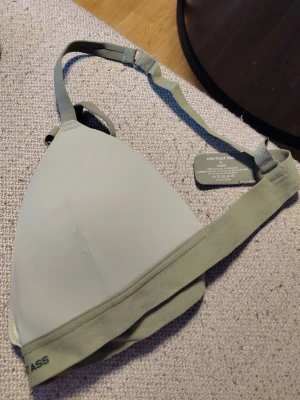 Ljusgrön bralette från ON THAT ASS - Stilren ljusgrön bralette från ON THAT ASS i modellen Isabel. Bh:n har justerbara axelband och bred resår under bysten för extra komfort. Tillverkad i 85% polyamid och 15% elastan för en mjuk och stretchig känsla.