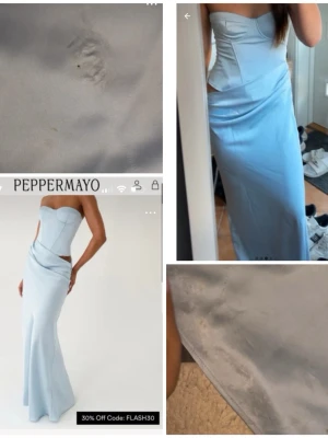 Ljusblå långklänning från Peppermayo - Elegant ljusblå långklänning från Peppermayo med axelbandslös design och figurnära passform. Klänningen har en unik cut-out detalj vid midjan och är tillverkad i ett glansigt material som ger en lyxig känsla. Har märken nertill på klänningen som man ser på bilden 
