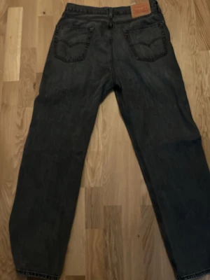 Levis 565 Loose fit - Säljer ett par svarta jeans med rak passform och hög midja. Jeansen har klassiska bakfickor och bälteshällor. Materialet är denim i bomull och färgen är tvättad svart för en vintagekänsla. Perfekta till en avslappnad streetwear-look.