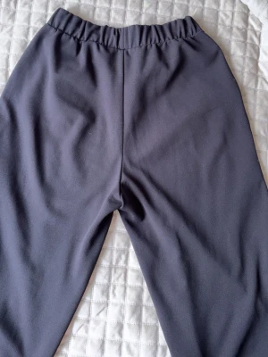 Svarta mjuka byxor  - Svarta mjuka byxor med resår i midjan och raka ben. Byxorna har en enkel och stilren design utan synliga loggor eller tryck. Tillverkade i ett mjukt och bekvämt material som passar perfekt att gå ut i. 