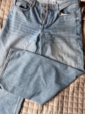 Baggy ljusblå jeans &Denim - Säljer ett par ljusblå baggy jeans från &Denim i storlek EUR 40. De har loose fit, låg midja och raka ben. Dem är långa. Klassisk femficksmodell med knappgylf och slitstarkt denimtyg. 