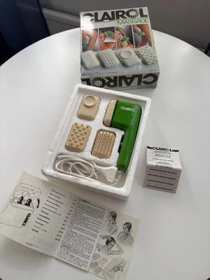 Clairol elektrisk massageapparat - Elektrisk massageapparat från Clairol i grön plast med tre utbytbara massagehuvuden i beige. Perfekt för avslappning och muskelmassage. Kommer med originalkartong, bruksanvisning och sladd för eluttag.