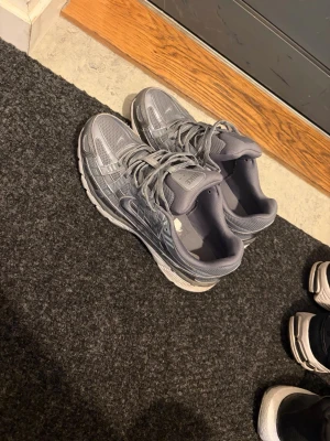 Grå Nike sneakers med meshdetaljer - Snygga grå sneakers från Nike med meshpaneler och reflexdetaljer. Skorna har en sportig look med vita sulor och klassisk Nike-logga på sidan. Perfekta för dig som gillar stilrena och bekväma sneakers.