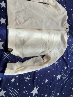 Vit stickad kofta med dragkedja - Helt ny Kofta i mjuk, vit stickad kvalitet med hel dragkedja framtill. Ribbstickade muddar vid ärmslut och nederkant samt diskreta mörka detaljer vid kanterna. Hög krage för extra komfort och stilren look.Från Jack and Jones. Storlek S men passar M och kanske L!