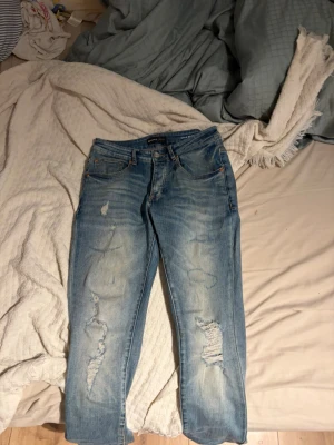 Amiri purple jeans Ljusblå slitna jeans med raka ben - Säljer ett par ljusblå amiri jeans med raka ben och slitningar på både fram- och baksida. Jeansen har klassisk femficksdesign och tydliga slitdetaljer på låren och knäna för en trendig look. Perfekta för dig som gillar en avslappnad och cool stil.