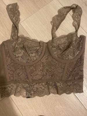 Beige spetsbh med breda axelband - ( Oanvänd Har prislapp kvar! )Supersnygg beige spetsbody med breda axelband och vacker blommig spets. Modellen har bygel och ger bra stöd, samt en feminin skärning med dekorativ kant nertill. Perfekt för dig som vill ha något både bekvämt och stilrent i garderoben.