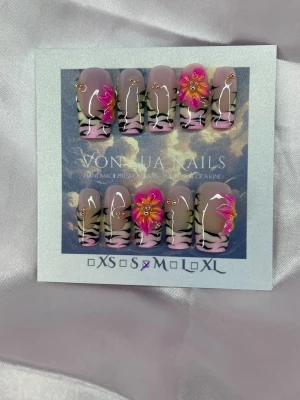 Zaria (M);Medium Square - Snygga press-on naglar i coffin-form med rosa och nude bas, zebramönster och 3D-blommor i rosa och orange. Naglarna har gulddetaljer och en glansig finish. Perfekt för dig som vill sticka ut med en unik och kreativ design.