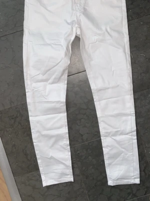 Vita skinny jeans storlek 28 - Säljer ett par vita skinny jeans i storlek 28. Jeansen har en klassisk femficksmodell och är tillverkade i ett stretchigt material som sitter tight längs benen. Perfekta för dig som vill ha en clean och fräsch look till vardags.